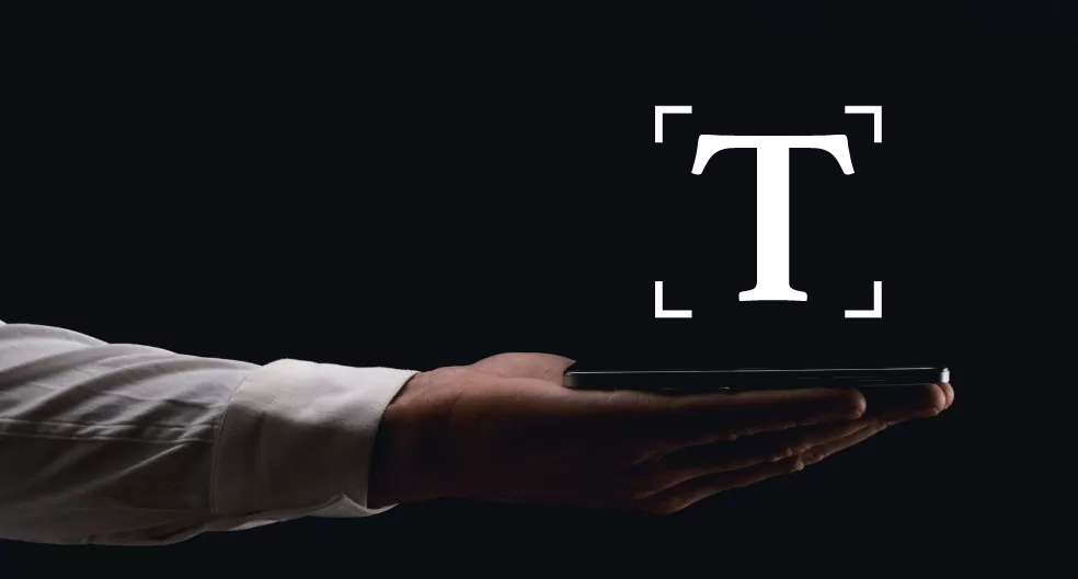 a hand holding a tablet and (T) writing content is showing above that
